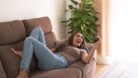 woman enjoying in living room with tv remote in hand