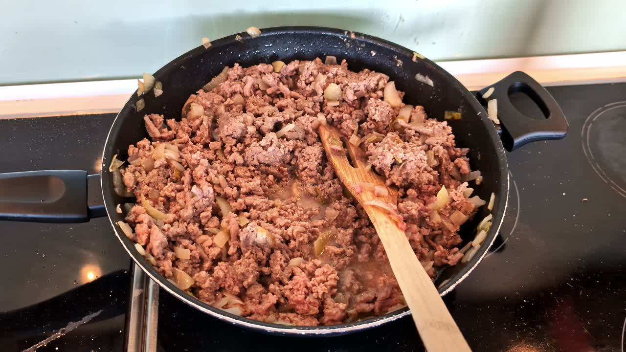 Cooking minced meat with onion in pan, close up