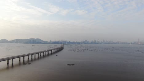 hong kong shenzhen bay bridge with tin shui wai buildings in the horizon and fish and oyster cultivation pools, aerial view