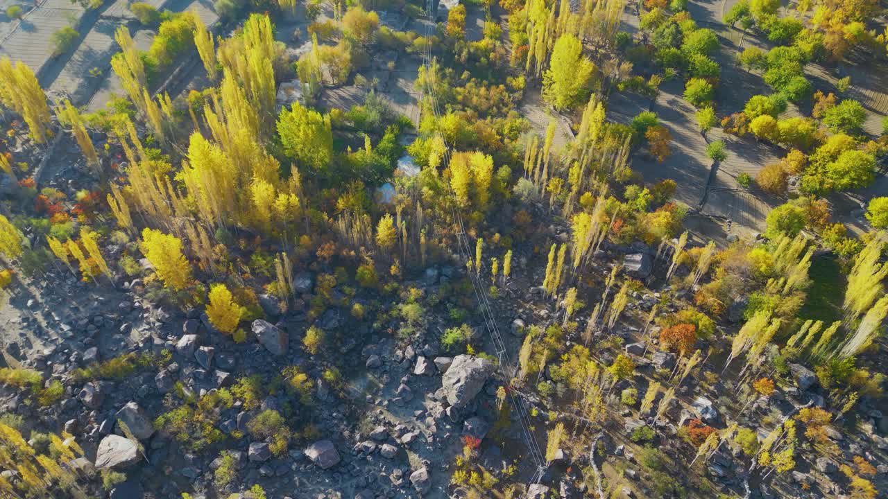 Capturing the stunning aerial view of skardu valley with vibrant autumn foliage, town structures, and majestic mountains under golden sunlight