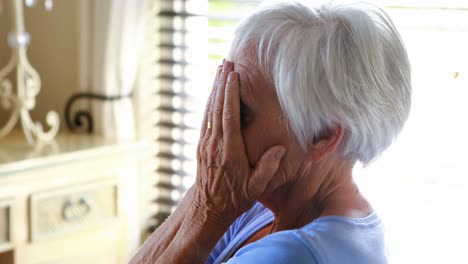 stressed senior woman covering her face with hands