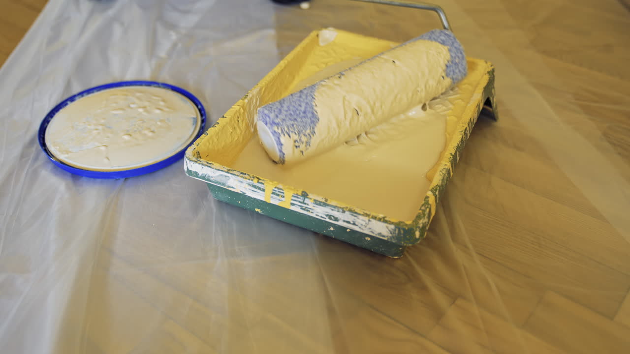Paint tray with a roller. Worker is typing creamy color on a paint roller before painting walls. Dye in paint tray. Close-up.