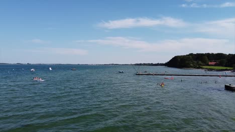 aerial baltic sea, pier leading into ocean and tourists swimming and enjoying the sunny weather