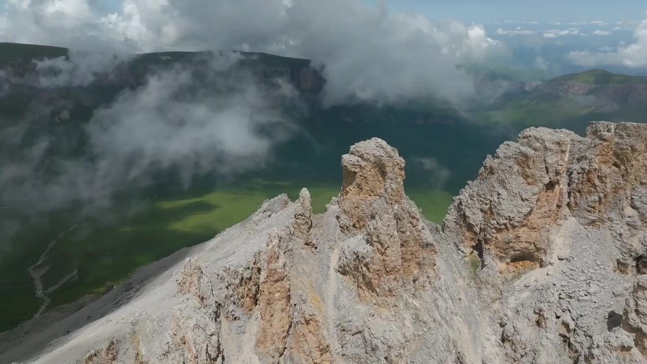 Naudzhidza Dağı'nın, sivri kireçtaşı kayalıkları, yeşil vadileri ve hareketli bulutlarıyla, Kabardey-Balkarya, Rusya'da, dramatik bir yaz dağ manzarasıyla drone çekimi.