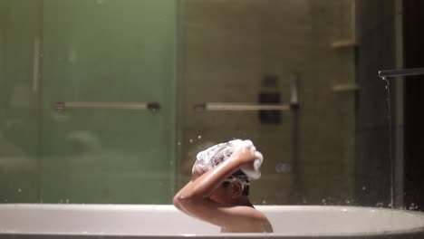 funny asian boy singing while shampooing when bathing on bathtub