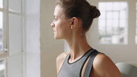 portrait healthy caucasian woman ready for yoga exercise looking out window planning ahead enjoying healthy lifestyle in fitness studio