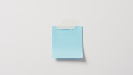 vídeo de un primer plano de una nota azul con un espacio de copia pegado a un fondo blanco
