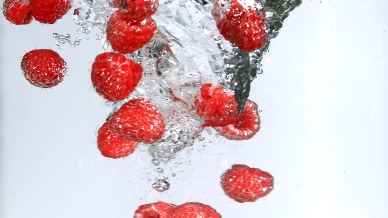 Slow Motion of Red Raspberries Splashing into Water