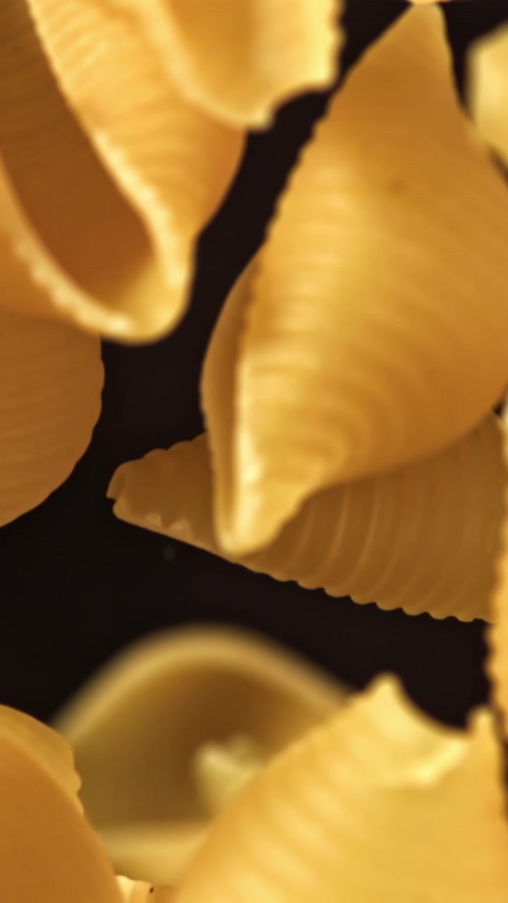 Primo piano di conchiglie di pasta crude che entrano a fuoco