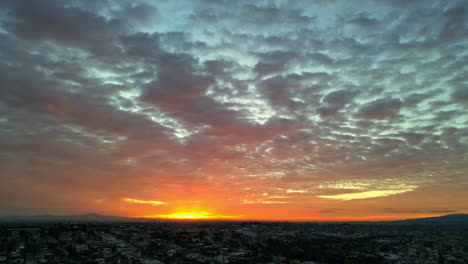 The-sun-rises-just-above-the-horizon-in-a-cloud-covered-sky-over-a-city