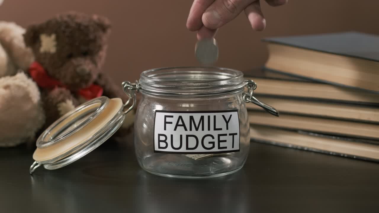 Lägger mynt i burk med texten Familjebudget