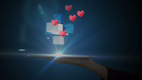pink hearts and 3d cubical shapes over hand holding a digital tablet against blue background