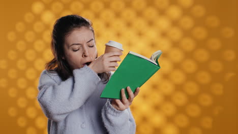 exhausted woman reading book, drinking coffee to stay awake, studio background