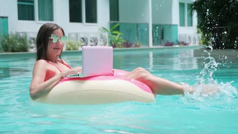 young woman swims in the sea in a swimming circle. girl resting in the pool on an inflatable circle with a computer, top view