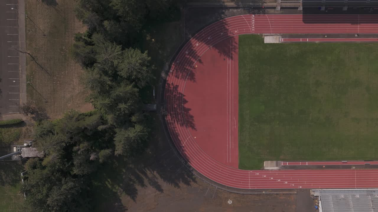 Wide overhead drone shot revealing a stadium field and running track