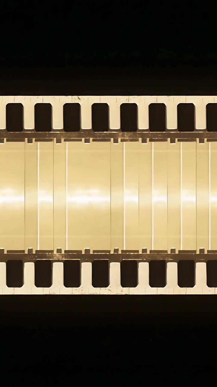 Video verticale: Motore che si innesta, una guida che muove una striscia perforata attraverso una retroilluminazione ambrata per la scansione.