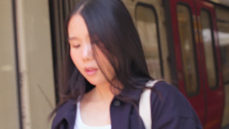 열차 가 도착 할 때 지하철 역 플랫폼 에서 휴대 전화 를 들고 기다리는 젊은 여자