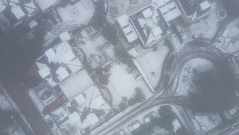 top down aerial of snow covered neighborhood in cold weather conditions