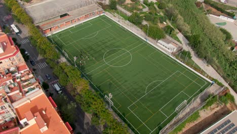 drones orbitan el campo de fútbol, capturando a los jugadores entrenando en medio de un entorno urbano.