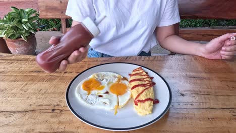 person artistically drizzling sauce over breakfast