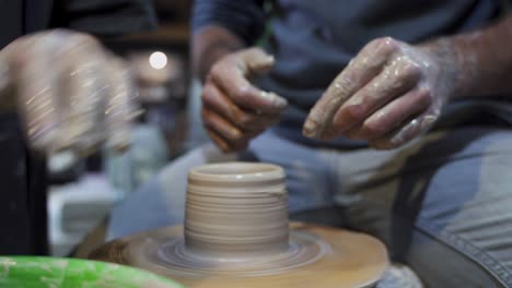 clase de cerámica: manos moldeando arcilla en la rueda de cerámica