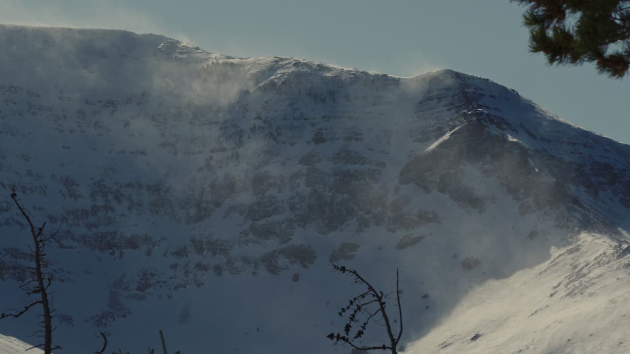 Panning up a mountain valley to the peak during a winter windstorm in the rocky mountains