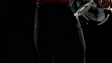 american football player holding a head gear under his arms 4k