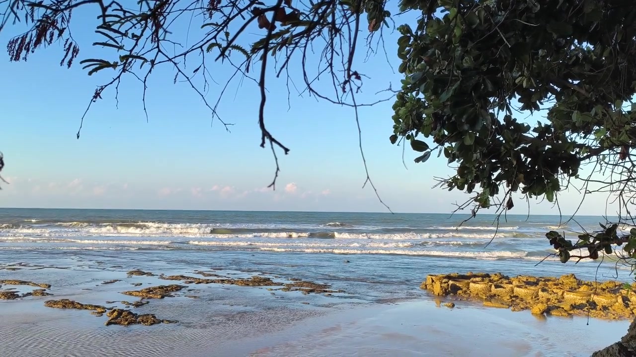 Gentle Waves Rolling onto a Rocky Tropical Beach at Sunset