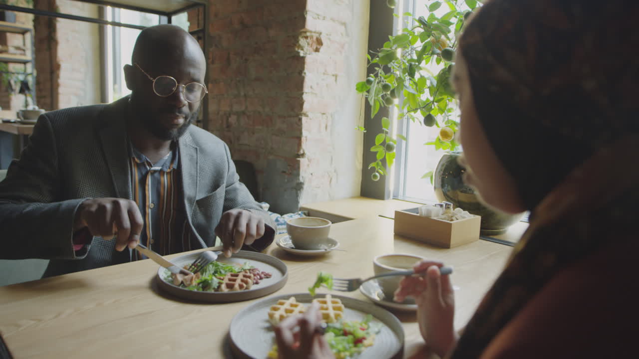 Businessman Talking with Female Colleague on Lunch in Cafe