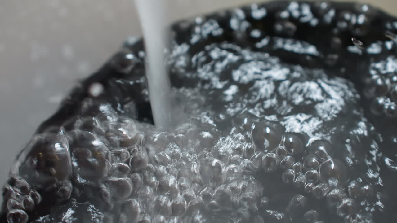 Close up detailed view of water rushing into bucket, liquid filled to brim with bubbles and overflow, surface tension and movement visible, capturing concept of cleaning and household use