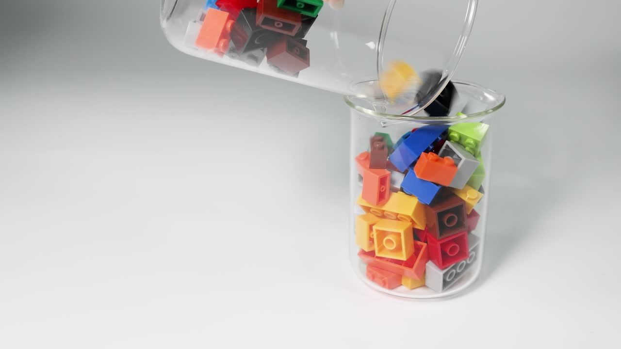 vertiendo ladrillos de lego de un frasco de vidrio a otro