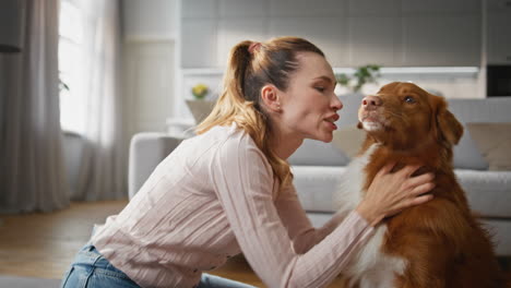 cheerful girl stroking dog in apartment close up. smiling woman caressing pet