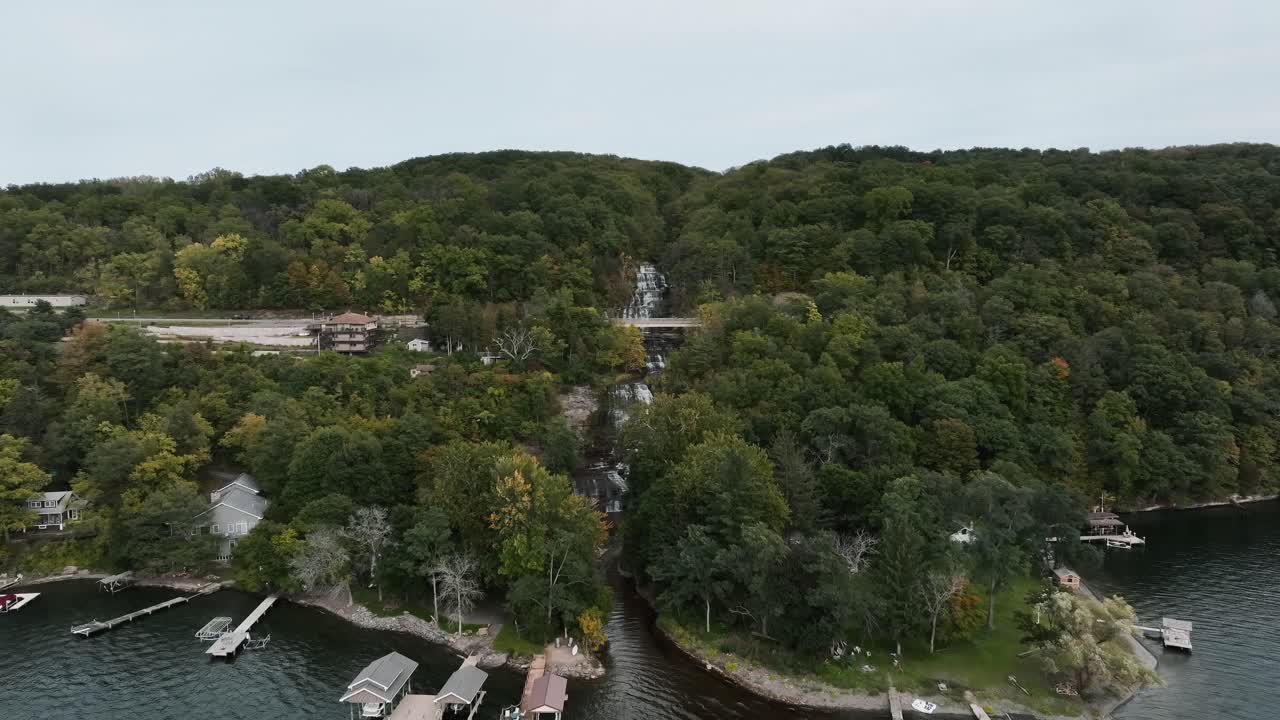 casas de botes y muelle con arroyo en cascada en el fondo sobre montañas forestales