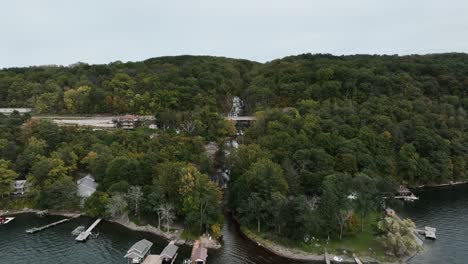 Boathouses And Jetty With Cascading Stream In The Background Over Forest Mountains