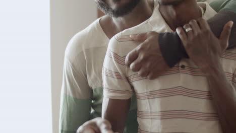 black man paying at terminal while his boyfriend hugging him.