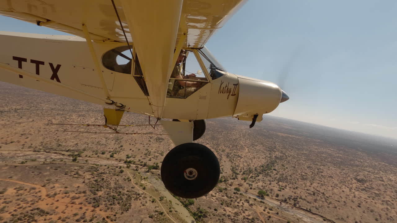 Piccolo aereo leggero che vola sopra un letto di fiume in una pianura keniota