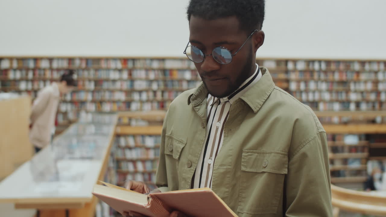 Afroamerikansk mand læser bog i bibliotek