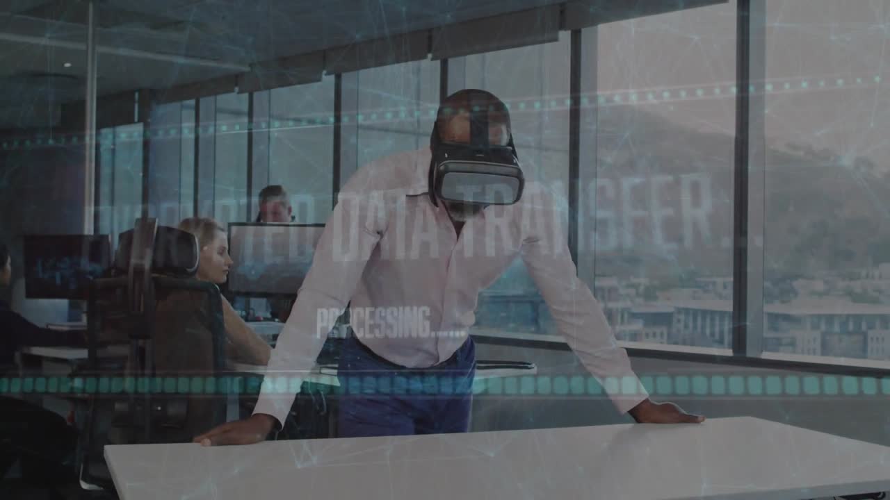 Ein reifer Mann setzt ein VR-Headset auf, das eine verschlüsselte Überlagerung über einem Bürotisch offenbart, während ein Kollege den Raum betritt.