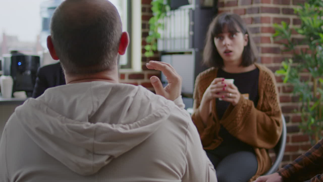 Man with anger management issues talking to people and counselor at aa group meeting