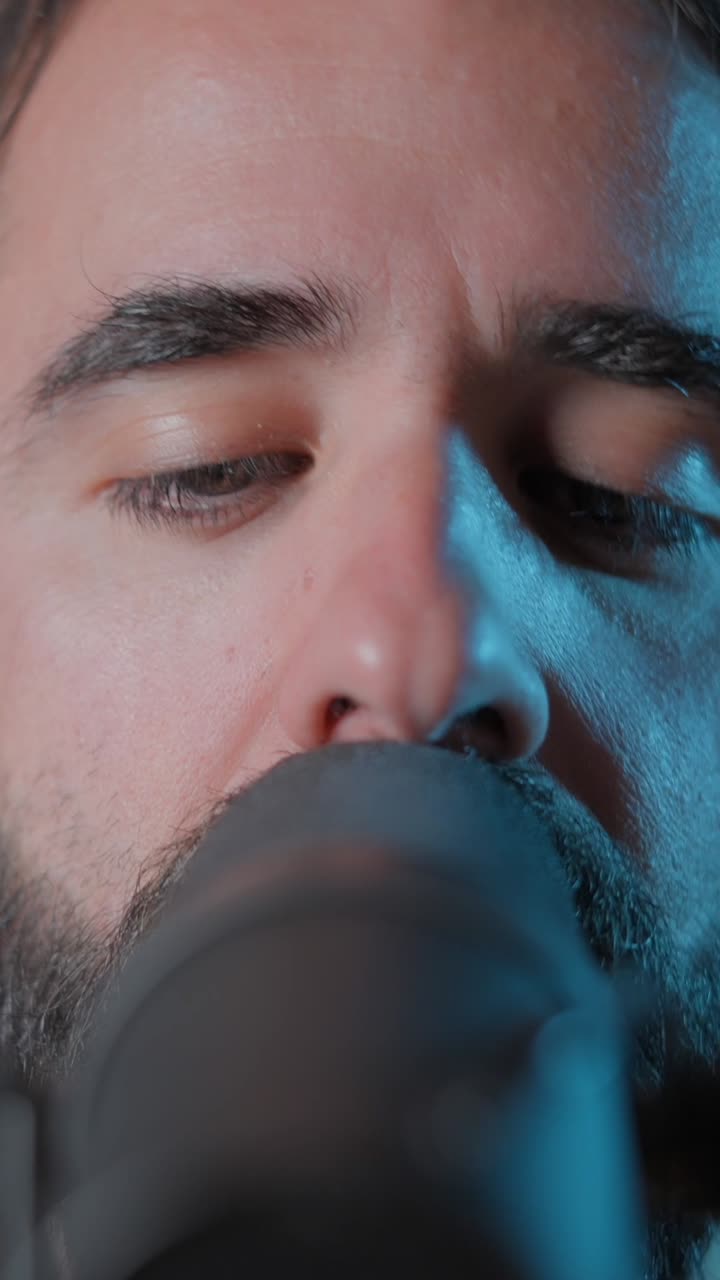 Close-up de um homem cantando no microfone com os olhos fechados