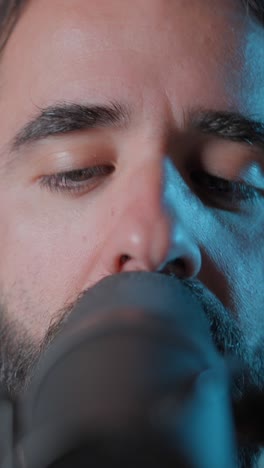 close-up of a man singing into a microphone with eyes closed