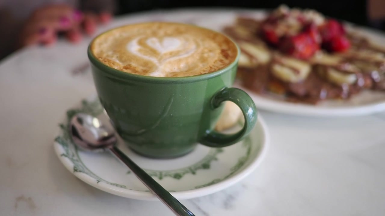 Tazza verde di cappuccino con latte art su un tavolino da bar