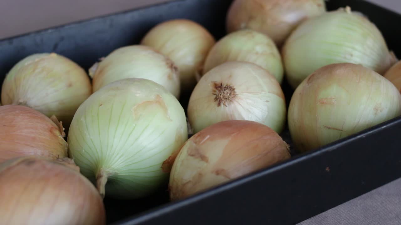 Pieces Of Whole White Onions In A Black Plastic Container