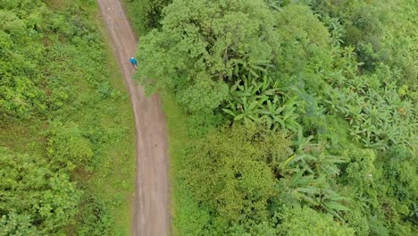 aerial shot of an indian male riding through the mountains route in a remote village, tamei, manipur, india