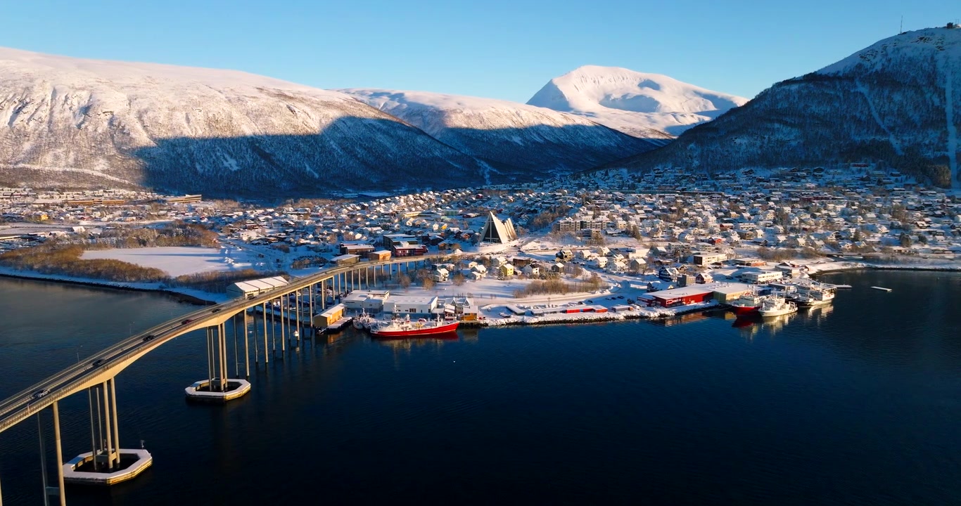 Ville enneigée, pont de Tromsø et emblématique Cathédrale Arctique par une lumineuse journée d'hiver, Norvège. Vue aérienne en avant, espace pour texte.