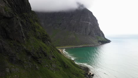 Cinematic-revealing-drone-shot-of-the-isolated-Kvalvika-Beach-in-the-Lofoten-Islands-Norway,-aerial-shot-with-turquoise-blue-water