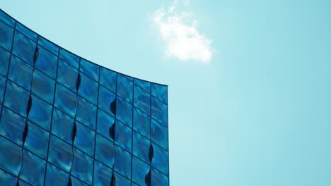 static, abstract shot of the modern glass fassade of the elbphilharmonie in hamburg, germany on a sunny day with blue skies