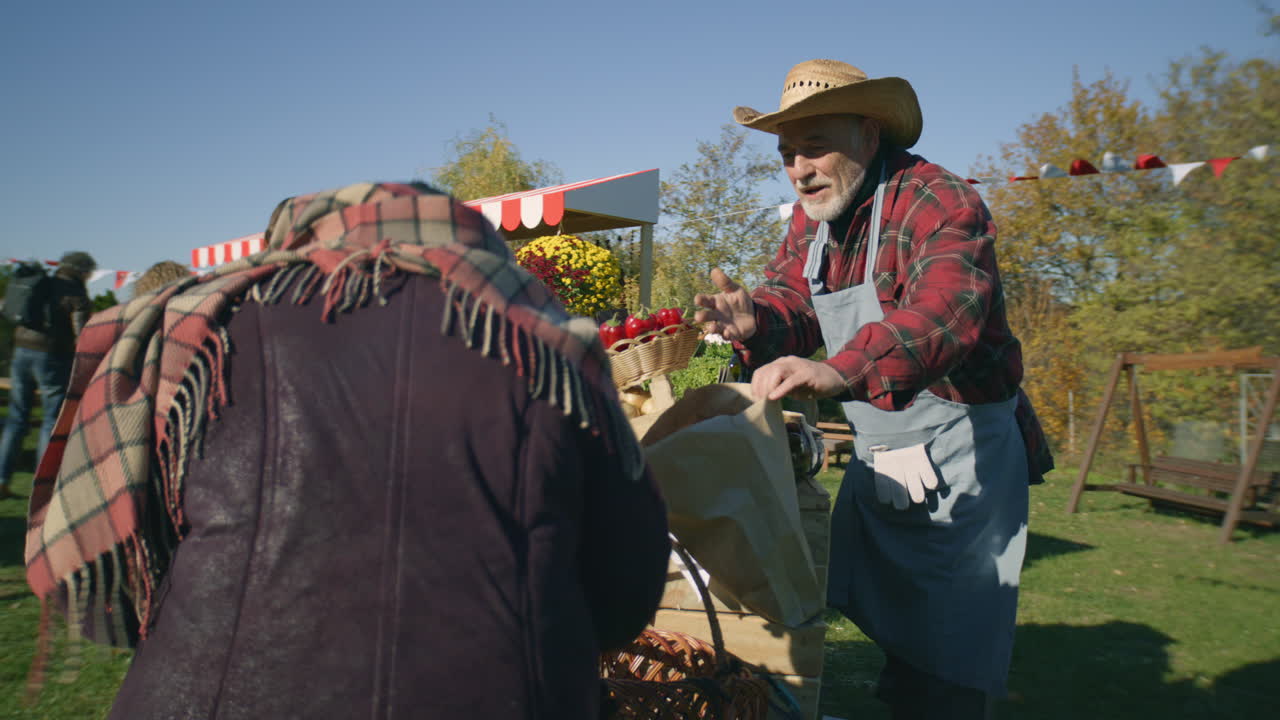 Elderly Woman Shopping at Farmers Market Elderly Woman Chooses Plums at the Stall with Fruits and Vegetables People Walking and Shopping on Background Local Farmers Market or Fair Outdoors Vegetarian and Organic Food Agriculture