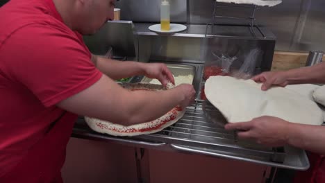 kitchen staff assembling dough, sauce and other ingredients for pizzas