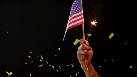 animation of confetti falling over hand holding flag of united states of america and sparkler